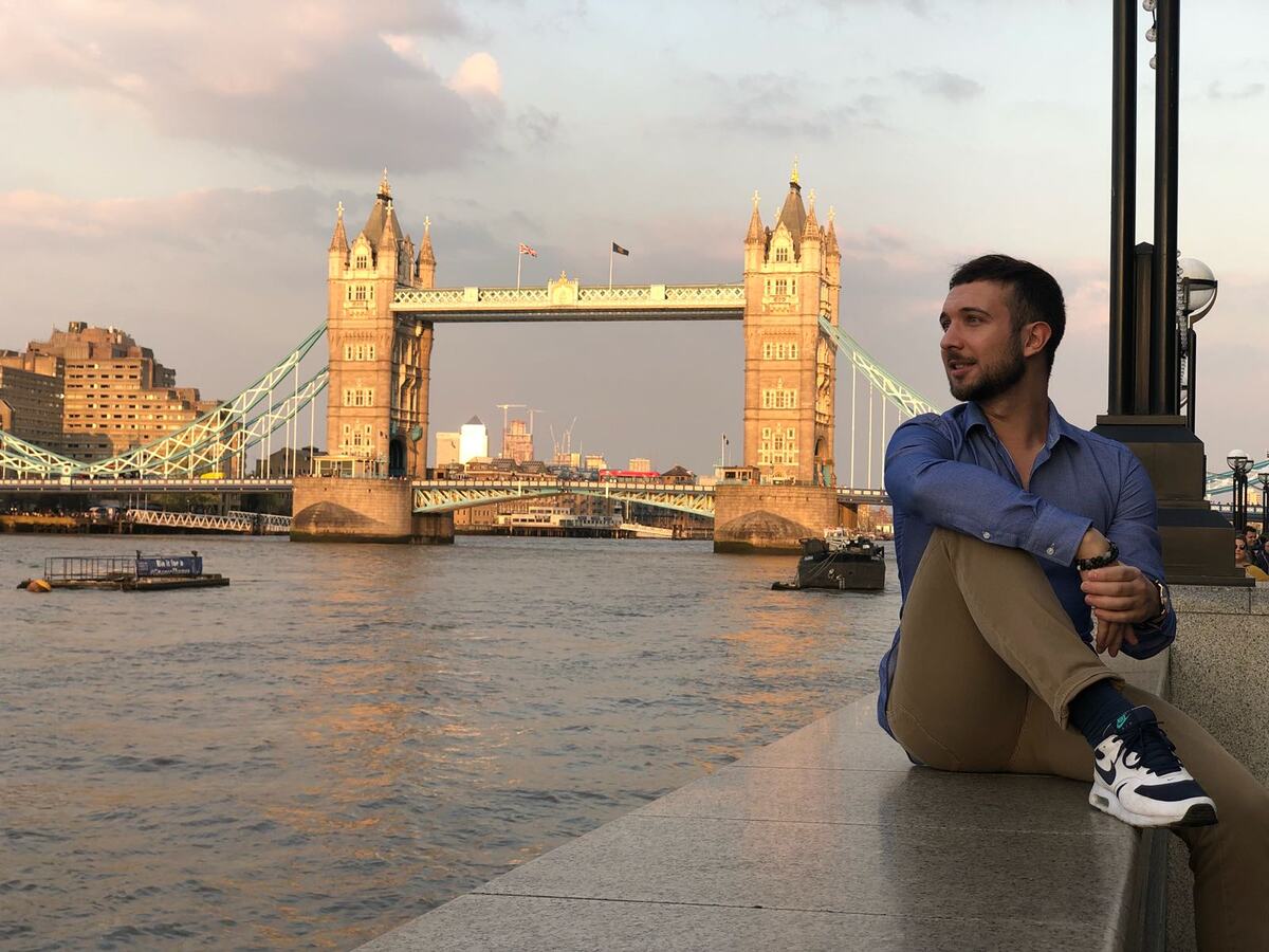 Daniele seduto sul lungofiume a Londra, sullo sfondo il Tower Bridge