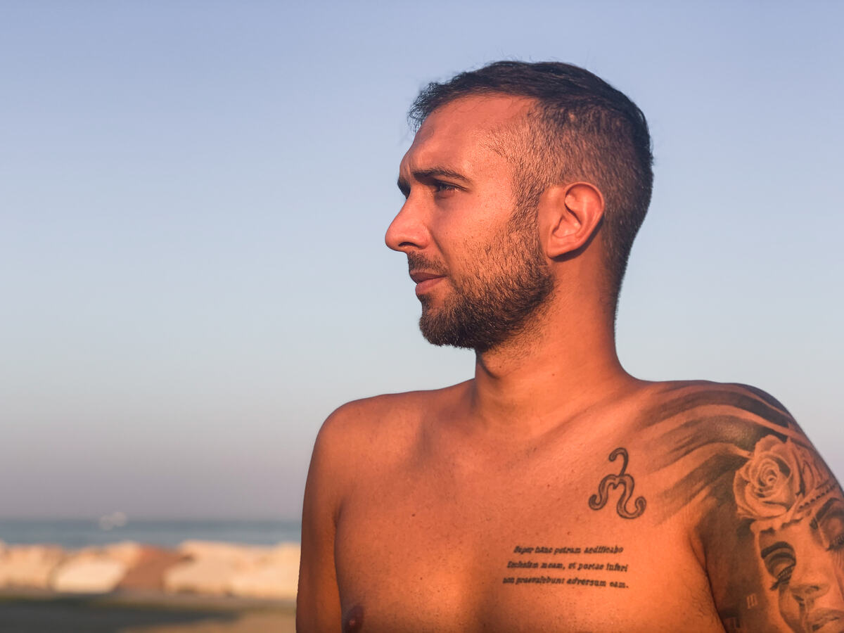 Daniele di profilo in controluce sulla spiaggia al tramonto
