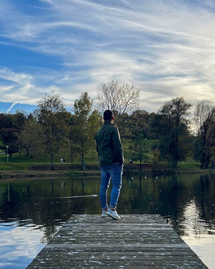 Daniele di spalle su un pontile, davanti a un lago, in un momento di riflessione