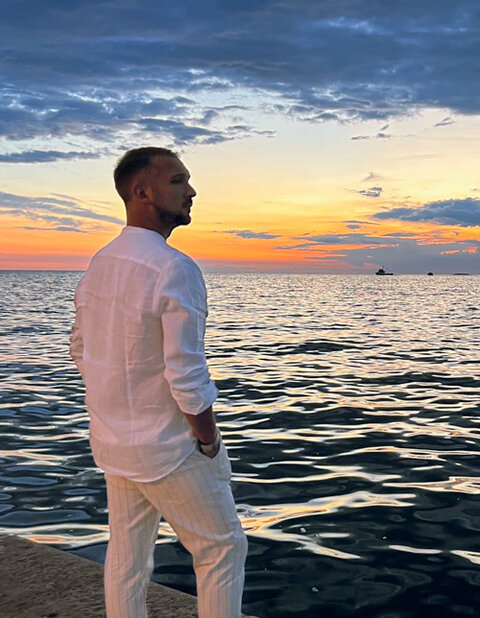 Daniele di spalle al tramonto, guarda l'orizzonte sul mare