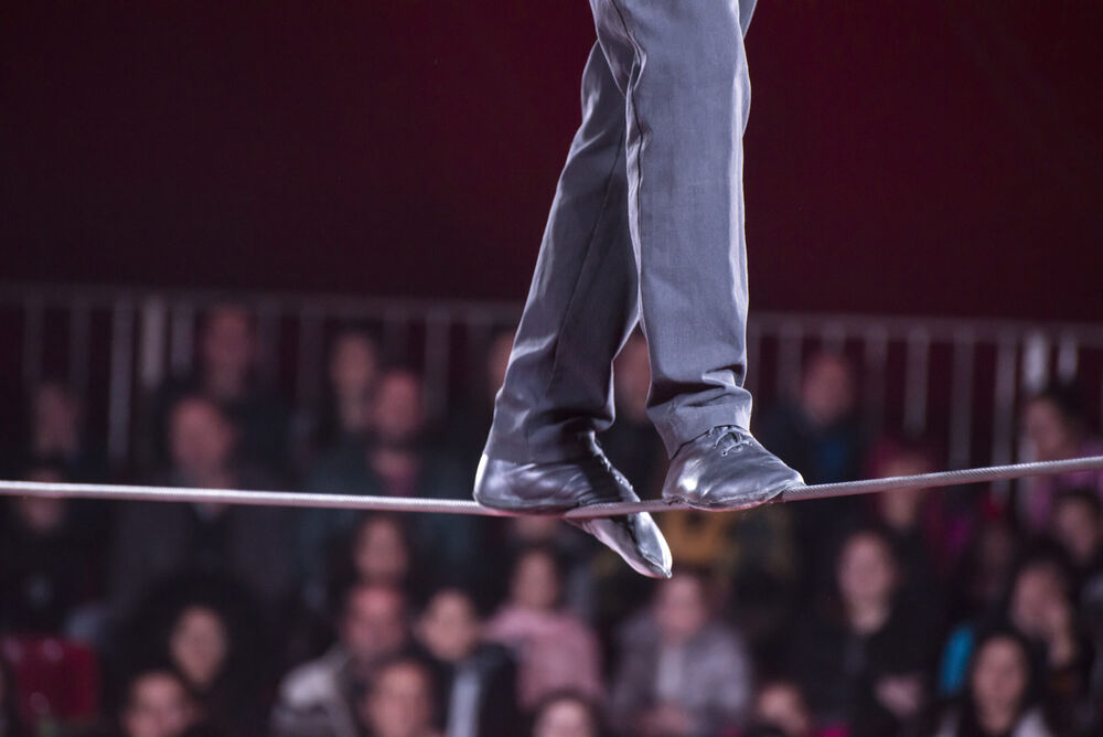 Funambolo che cammina su una corda sospesa sotto un tendone da circo